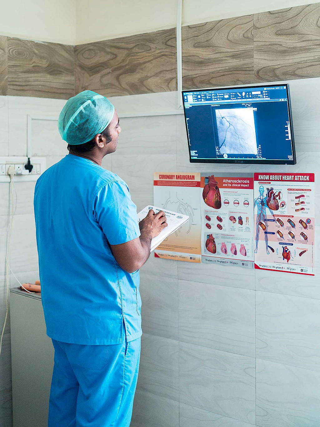 In the anteroom of the cath lab, Rajaram Prasad, MD, stands in front of a monitor on the wall and studies a clinical image.