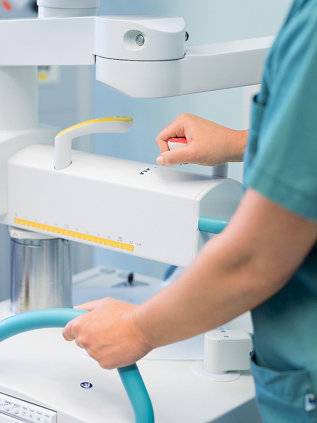 Two members of the surgical team stand in front of a small monitor displaying the user interface for controlling a C-arm.