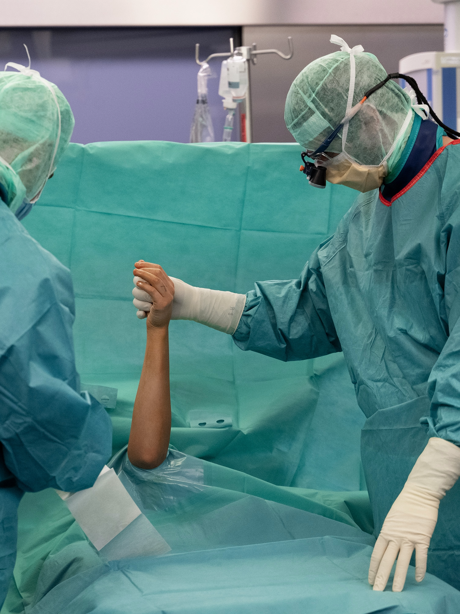 Zwei Ärzte im OP-Saal halten die Hand eines Patienten